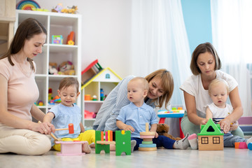  Group of happy moms with their babies in nursery or playroom
