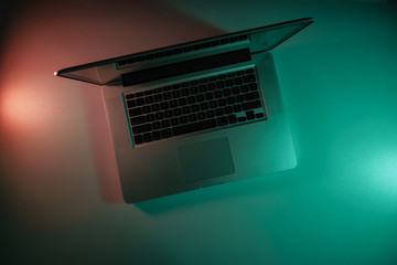 Aufkleber - Beautiful silver laptop in the color light on a table and night background. Top view.