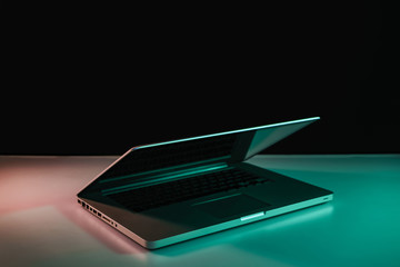 Aufkleber - Beautiful silver laptop in the color light on a table and night background.