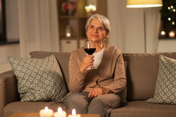 Canvas Print - people, alcohol and drinks concept - happy senior woman drinking red wine from glass at home in evening