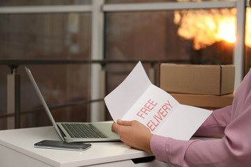 Sticker - Woman with note Free Delivery working at table indoors, closeup. Courier service