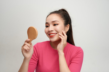 Wall Mural - Head shot of young woman holding mirror and touching her face