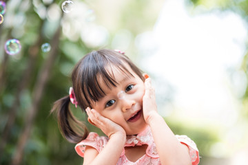 Cute asian little girl is acting and smiling with fully happiness moment during playing the soap bubbles, concept of happy and healthy kid lifestyle.