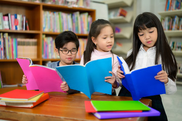 Wall Mural - Asian Kids Reading Book in School Library with a Shelf of Book in Background, Asian Kid Education Concept