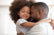 Happy biracial dad and daughter cuddle at home