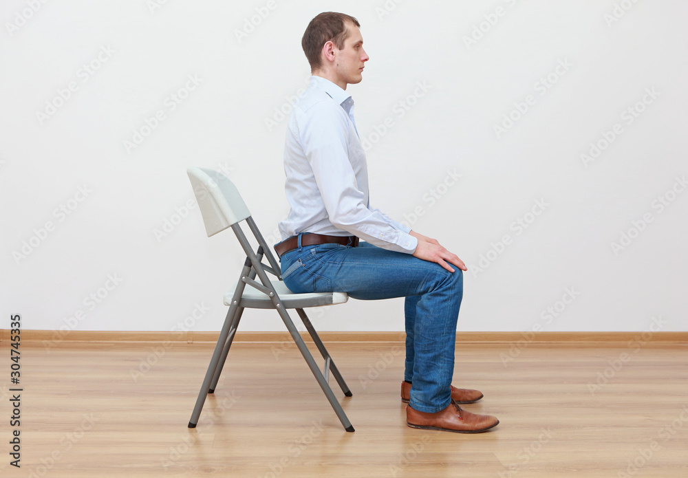 caucasian man sitting on the edge of chair in correct  posture - obrazy, fototapety, plakaty 