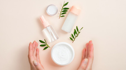 Wall Mural - jar of organic hand cream, essential oils bottle and green leaves on beige background. skin care, or