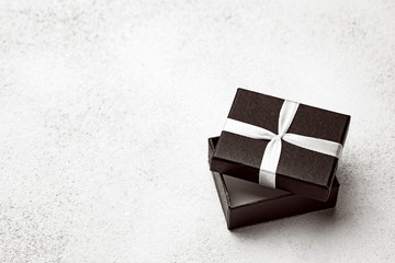 Open black box with white ribbon on a light background. Gift wrapping with empty place for text.