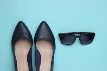 Stylish female look. Leather high heel shoes and sunglasses on a blue background. Top view