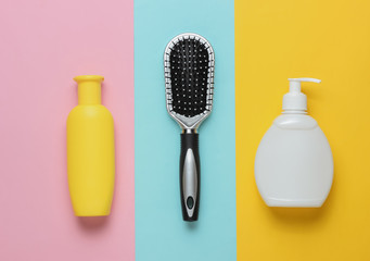 Minimalistic beauty concept. Hair care. Comb and bottles of shampoo on colored pastel background. Top view