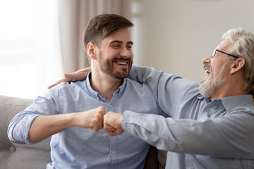 Wall Mural - Happy young son and old father fists bumping, having fun