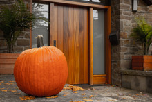 Large Pumpkin Standing At The Front Doors Outside Of The Fancy Home. Season Outdoor Decoration For The Halloween In USA And Canada.