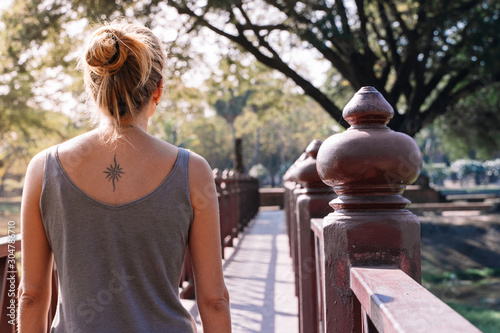 young blonde woman seen from behind on a bridge walking in nature with  tattoo on her back - Buy this stock photo and explore similar images at  Adobe Stock | Adobe Stock