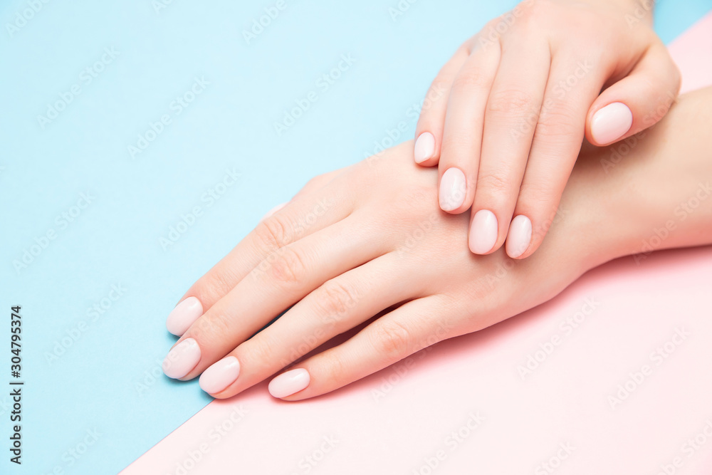 Fotografering Beautiful female hands with stylish nail manicure gel polish on pink and blue background, top view