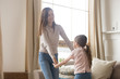 © fizkes - Smiling mom and little daughter dancing playing at home