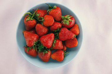 Wall Mural - Ripe strawberries in a blue bowl on a white tablecloth. Copy space for text.