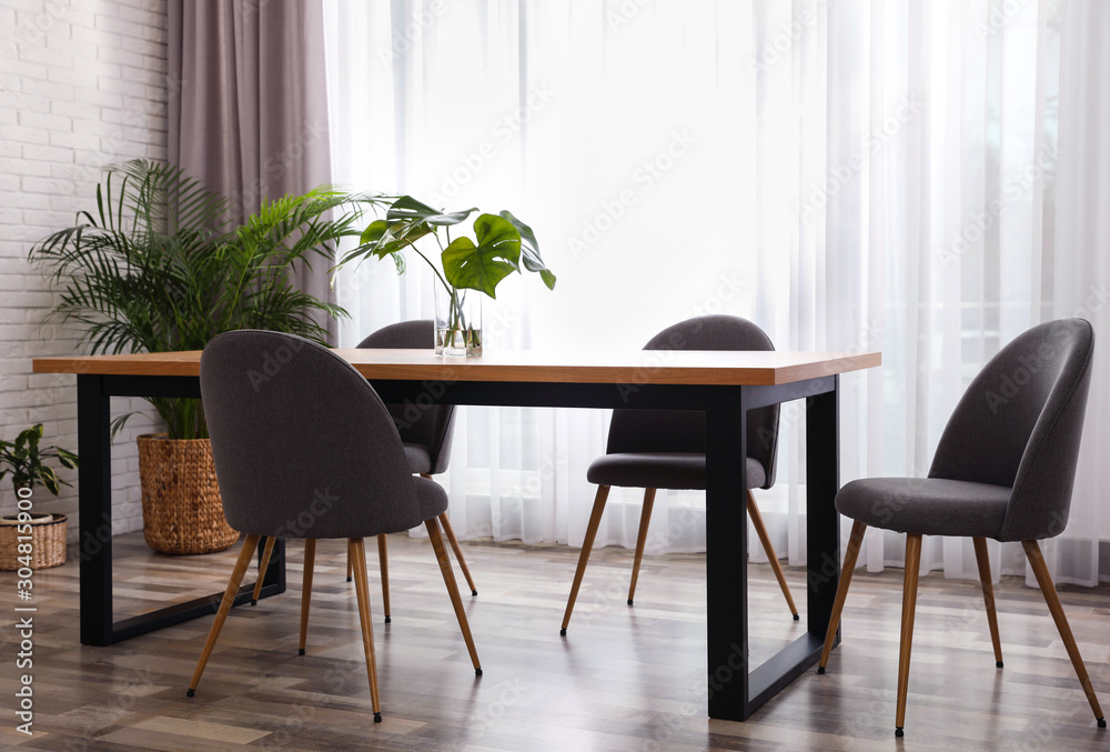 Fresh leaves of tropical plants on table in room. Home decoration - obrazy, fototapety, plakaty 