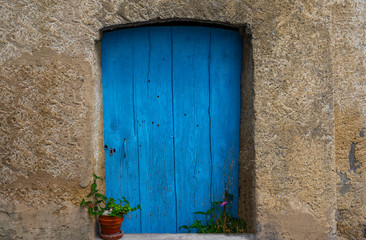 Wall Mural - Old building in France. Wall with blue door and flower pot. Building with beautiful old architecture. Old door on old wall.