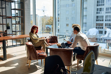 Business appointment at the office space with 3 caucasian people, two male workers listening to their female boss. Business woman reading out her prepositions and plans.