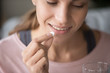 Smiling young woman having vitamins at home