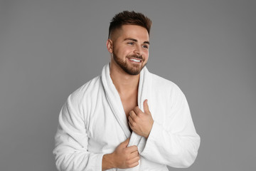 Poster - Happy young man in bathrobe on grey background