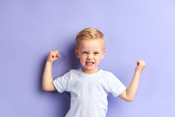 portrait of caucasian kid boy with blond hair showing muscles at camera, wearing white t-shirt. purp