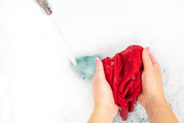 Wall Mural - Female hands washing color clothes with running water in the sink