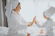 © alfa27 - family game at home. friendly beautiful mother and her daughter sit clapping hands, play with each other, wearing white bathrobe and towel