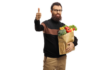 Canvas Print - Bearded man with a paper bag full of fruits and vegetables showing thumb up