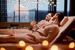 canvas print picture - Spa, relax, enjoying concept. Married couple together relaxing in spa salon, lying on beds drinking champagne, using candles