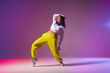 Cheerful energetic woman in casual outfit standing on tiptoe, bending back, showing sexy naked flat belly, performing dancing element on hip hop dance competition