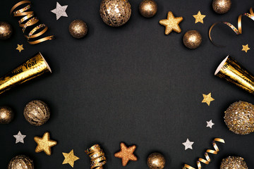 Poster - New Years Eve frame of glittery gold stars, streamers, decorations and noisemakers. Above view on a black background.