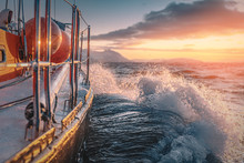 A Boat Sailing On Norway Sea With Golden Splashes At Sunset Background