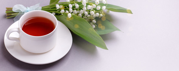 delicate bouquet of fresh lilies of the valley  and freshly brewed black tea on table, concept of beautiful freshness morning breakfast, spring season, romance, banner