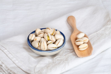 Canvas Print - Pistachio nut in wooden bowl on white table background