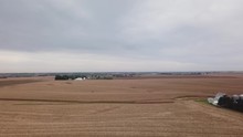 Aerial Drone View In Rural Iowa; Flying Over Harvested Corn Fields And A Soon To Be Harvested Corn Fields; Two Farmsteads Are Visible