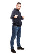 A young man in jeans in a fighting stance. Full height. Isolated over white background. Vertical.