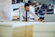 © Dusan Petkovic - Dedicated hardworking caucasian bearded graphic engineer in shit and tie standing in warehouse and searching appropriate sheet for printing machine.