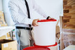 © Dusan Petkovic - Cropped picture of graphic engineer in shirt and tie taking bucket with liquid glue. Printing shop interior.