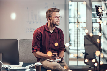 Young man is sitting with notebook at work