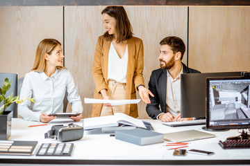 Wall Mural - Small group of creative office employees working together on some architectural project in the modern office. Concept of an architectural business and creative work