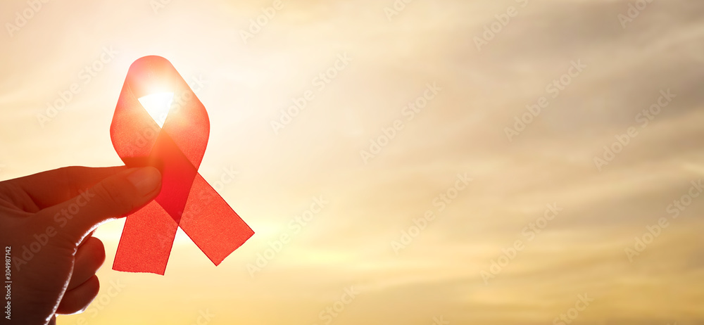 Red ribbon symbol of AIDS and HIV disease. - obrazy, fototapety, plakaty 