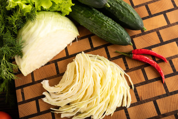 Cabbage, cucumbers and chilli on wooden cutting board