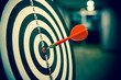 Red dart arrow  hitting in the target center of dartboard on bullseye for Business focus performance and target group concept.