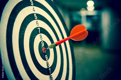 Fotografía Red dart arrow hitting in the target center of dartboard on bullseye for Business focus performance and target group concept