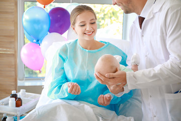 Wall Mural - Young woman with newborn baby and gynecologist in maternity hospital