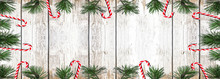 Christmas Background Panorama Banner Long - Frame Made Of Sweet Candy Canes And Pine Branches Isolated On White Shabby Vintage Wooden Texture - Top View With Space For Text