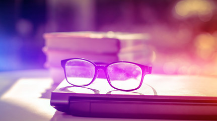 Poster - stack of books with glasses placed on the open book in library.