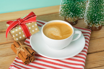 Wall Mural - Christmas holiday background with coffee cup, gift box and pine tree on wooden table.