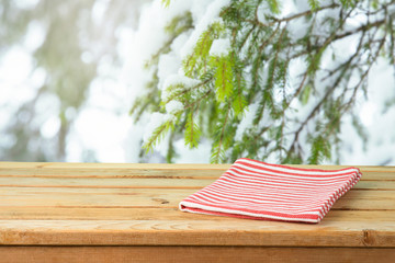 Poster - Empty wooden table with tablecloth over snow pine tree branches background